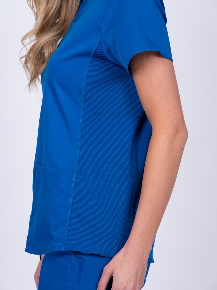 Woman wearing an Epic by MedWorks Women's Blessed Scrub Top in royal with side stretch panels to ensure a comfortable fit while moving.