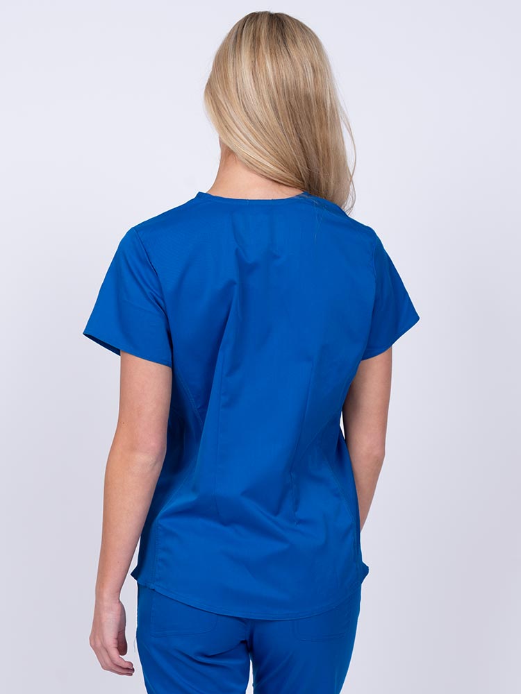Woman wearing an Epic by MedWorks Women's Blessed Scrub Top in royal with a pleated back for a flattering fit.