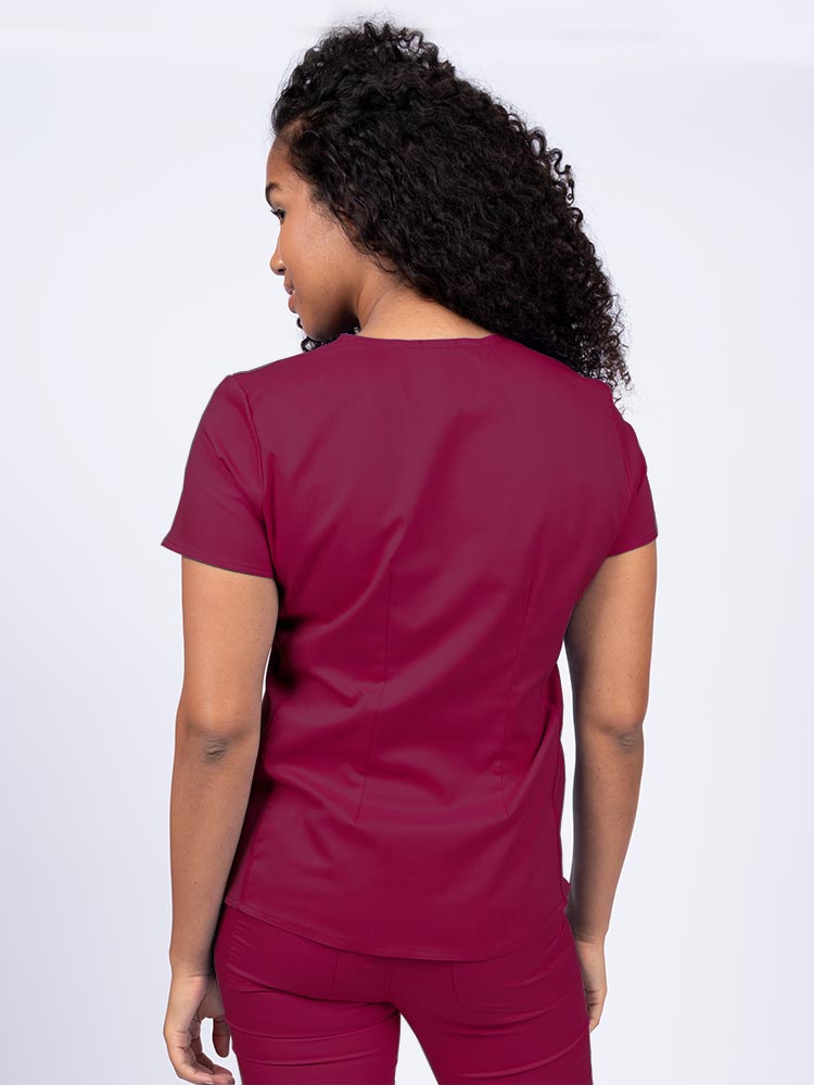Woman wearing an Epic by MedWorks Women's Blessed Scrub Top in wne with a pleated back for a flattering fit.