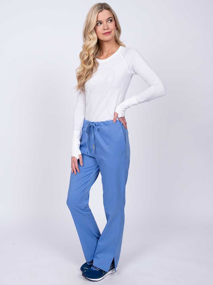 Woman wearing an Epic by MedWorks Women's Drawstring Flare Leg Scrub Pant in ceil featuring 2 front slash pockets.