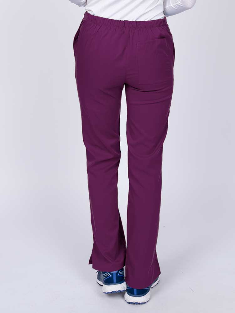 Young healthcare worker wearing an Epic by MedWorks Women's Drawstring Flare Leg Scrub Pant in eggplant featuring a drawstring waist with back elastic.