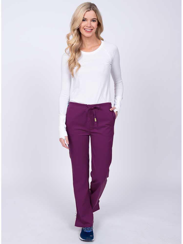 Woman wearing an Epic by MedWorks Women's Drawstring Flare Leg Scrub Pant in eggplant with 2 front slash pockets & 1 back pocket.