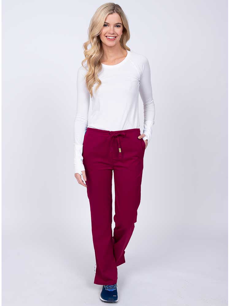 Woman wearing an Epic by MedWorks Women's Drawstring Flare Leg Scrub Pant in wine with 2 front slash pockets & 1 back pocket.