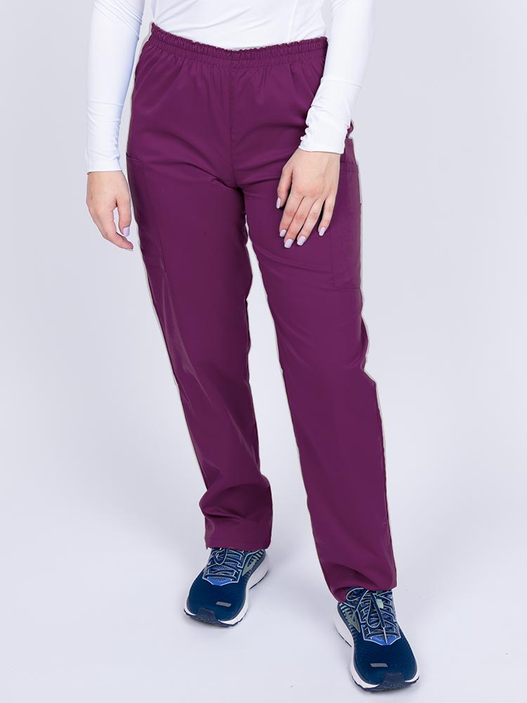 Young woman wearing an Epic by MedWorks Women's Elastic Waist Scrub Pant in eggplant featuring a tapered leg and elastic waist.