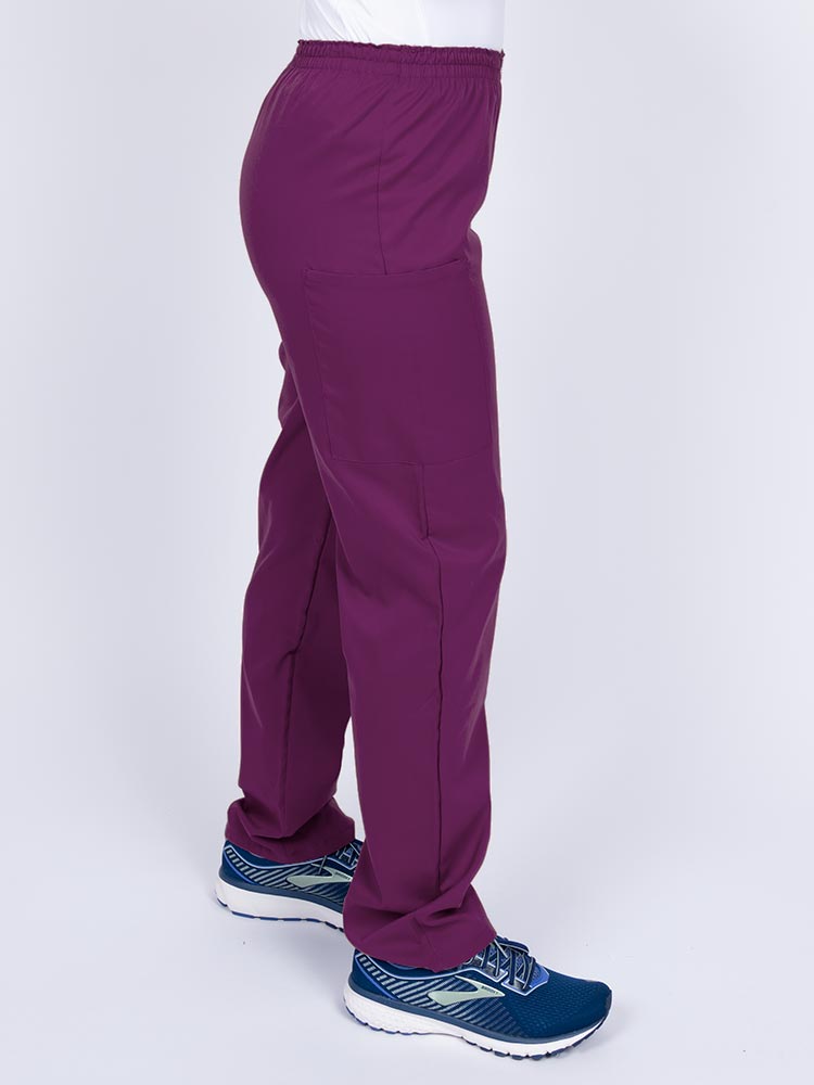 Woman wearing an Epic by MedWorks Women's Elastic Waist Scrub Pant in eggplant with two cargo pockets.