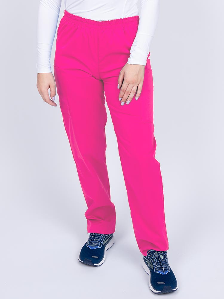 Young woman wearing an Epic by MedWorks Women's Elastic Waist Scrub Pant in shocking pink featuring a tapered leg and elastic waist.