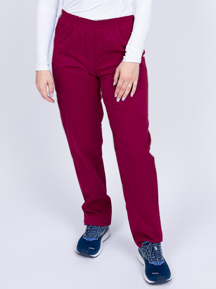 Young woman wearing an Epic by MedWorks Women's Elastic Waist Scrub Pant in wine featuring a tapered leg and elastic waist.