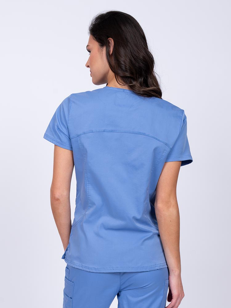 Young female nurse wearing an Epic by MedWorks Women's Knit Collar Mock Wrap Scrub Top in blue fog with stylish seaming throughout.