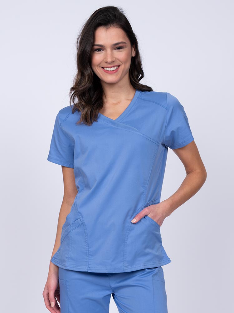 Young RN wearing an Epic by MedWorks Women's Knit Collar Mock Wrap Scrub Top in ceil featuring a Y-neckline with short sleeves.