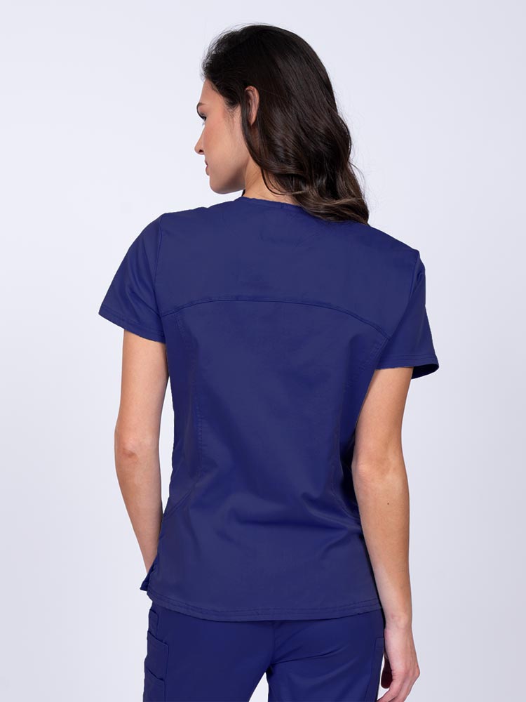 Young female nurse wearing an Epic by MedWorks Women's Knit Collar Mock Wrap Scrub Top in navy with stylish seaming throughout.