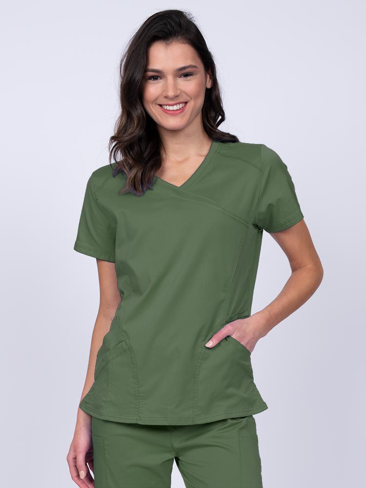 Young RN wearing an Epic by MedWorks Women's Knit Collar Mock Wrap Scrub Top in olive featuring a Y-neckline with short sleeves.