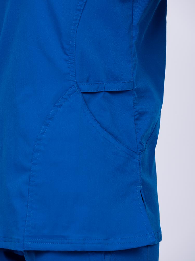 Young woman wearing an Epic by MedWorks Women's Knit Collar Mock Wrap Scrub Top in royal with a pen slot located on the wearer's left side.