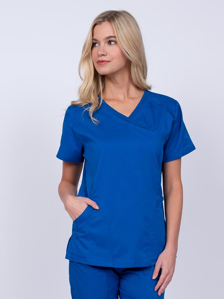 Young RN wearing an Epic by MedWorks Women's Knit Collar Mock Wrap Scrub Top in royal featuring a Y-neckline with short sleeves.