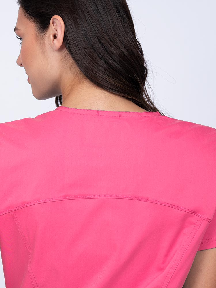Young woman wearing an Epic by MedWorks Women's Knit Collar Mock Wrap Scrub Top in shocking pink with a back yoke to ensure a flattering fit.