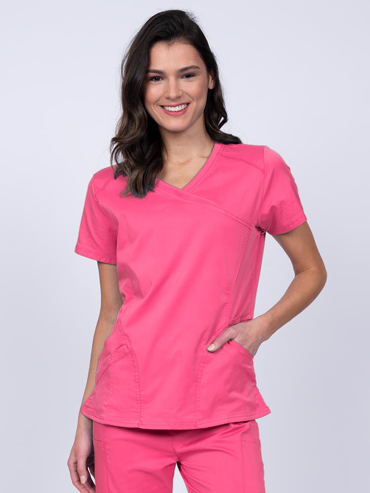 Young RN wearing an Epic by MedWorks Women's Knit Collar Mock Wrap Scrub Top in shocking pink featuring a Y-neckline with short sleeves.