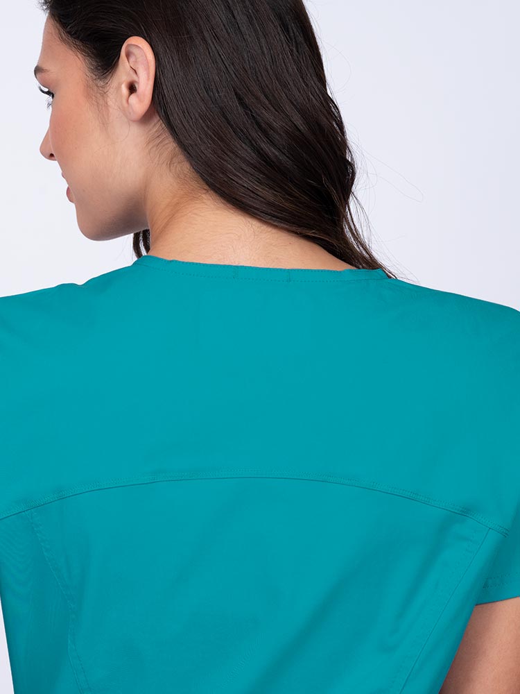 Young woman wearing an Epic by MedWorks Women's Knit Collar Mock Wrap Scrub Top in teal with a back yoke to ensure a flattering fit.