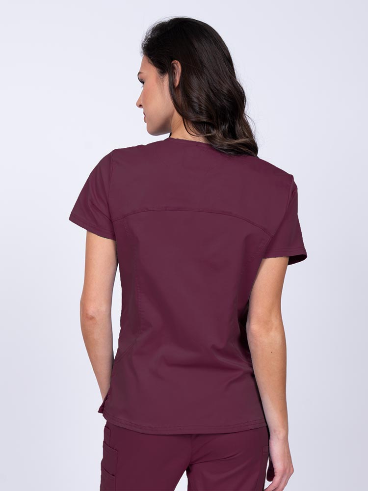 Young female nurse wearing an Epic by MedWorks Women's Knit Collar Mock Wrap Scrub Top in wine with stylish seaming throughout.