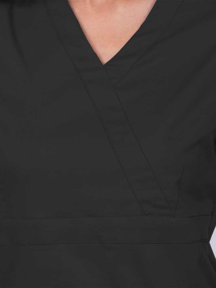 Young woman wearing an Epic by MedWorks Women's Mock Wrap Scrub Top in black featuring a mock wrap neckline and stylish front seaming.