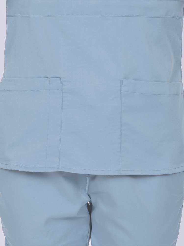 Woman wearing an Epic by MedWorks Women's Mock Wrap Scrub Top in blue fog featuring two front patch pockets.