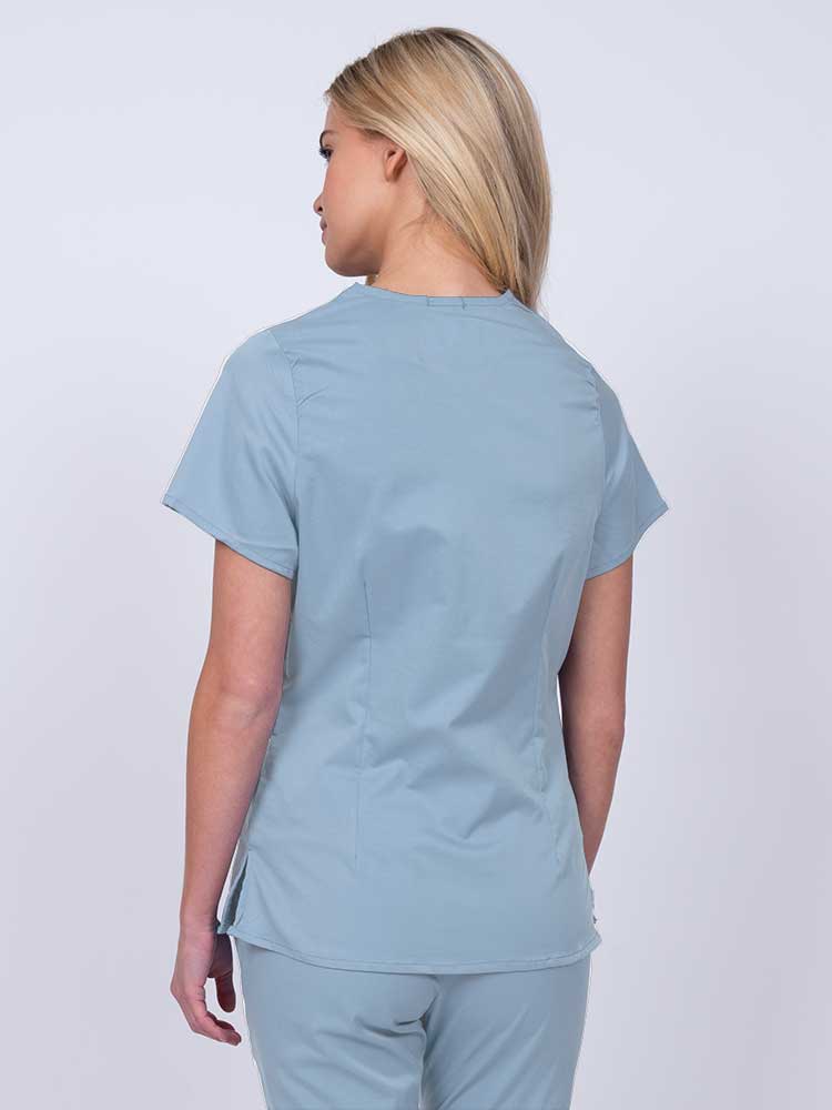 Nurse wearing an Epic by MedWorks Women's Mock Wrap Scrub Top in blue fog with side slits for additional range of motion.