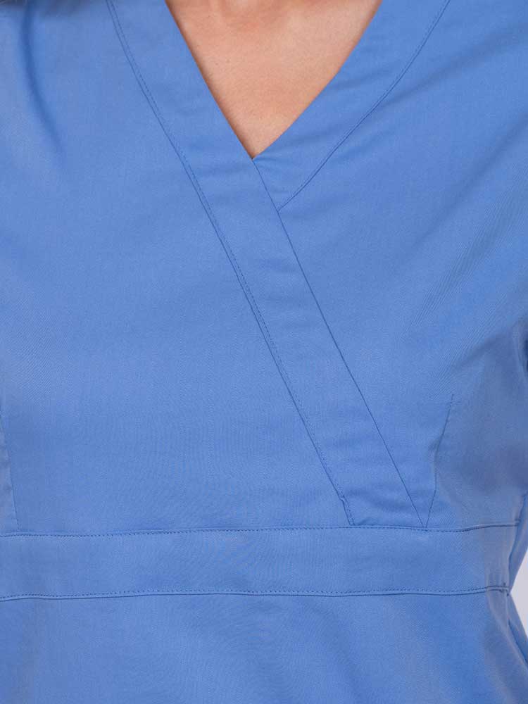 Young woman wearing an Epic by MedWorks Women's Mock Wrap Scrub Top in ceil featuring a mock wrap neckline and stylish front seaming.