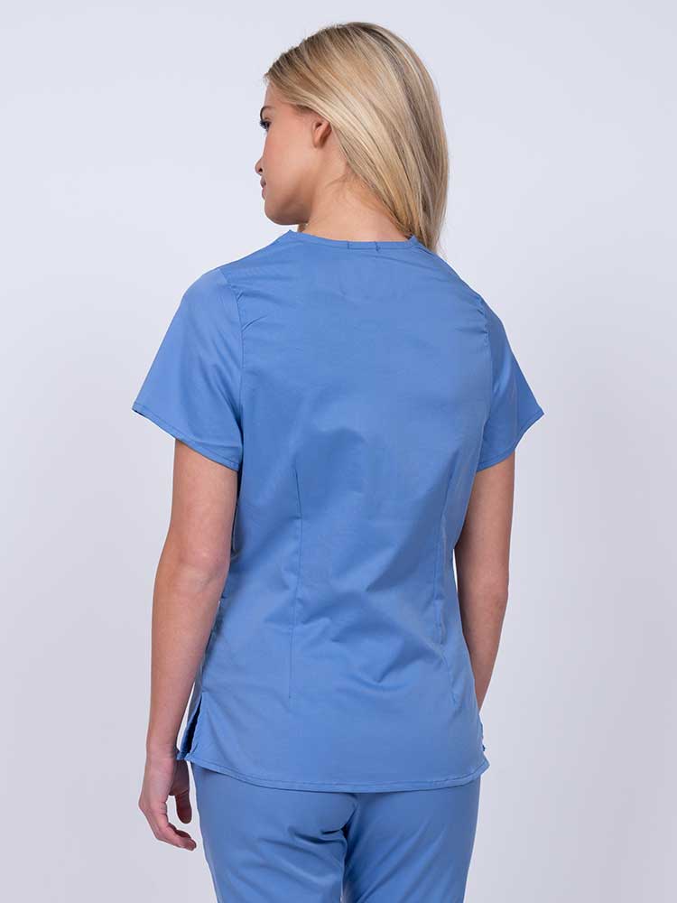 Nurse wearing an Epic by MedWorks Women's Mock Wrap Scrub Top in ceil with side slits for additional range of motion.