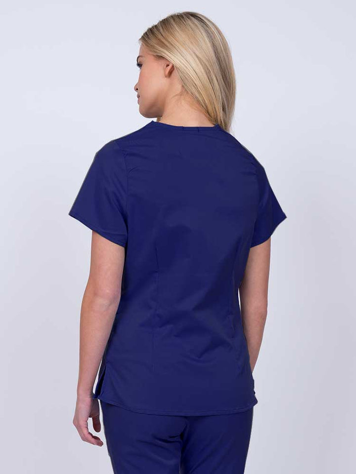 Nurse wearing an Epic by MedWorks Women's Mock Wrap Scrub Top in navy with side slits for additional range of motion.