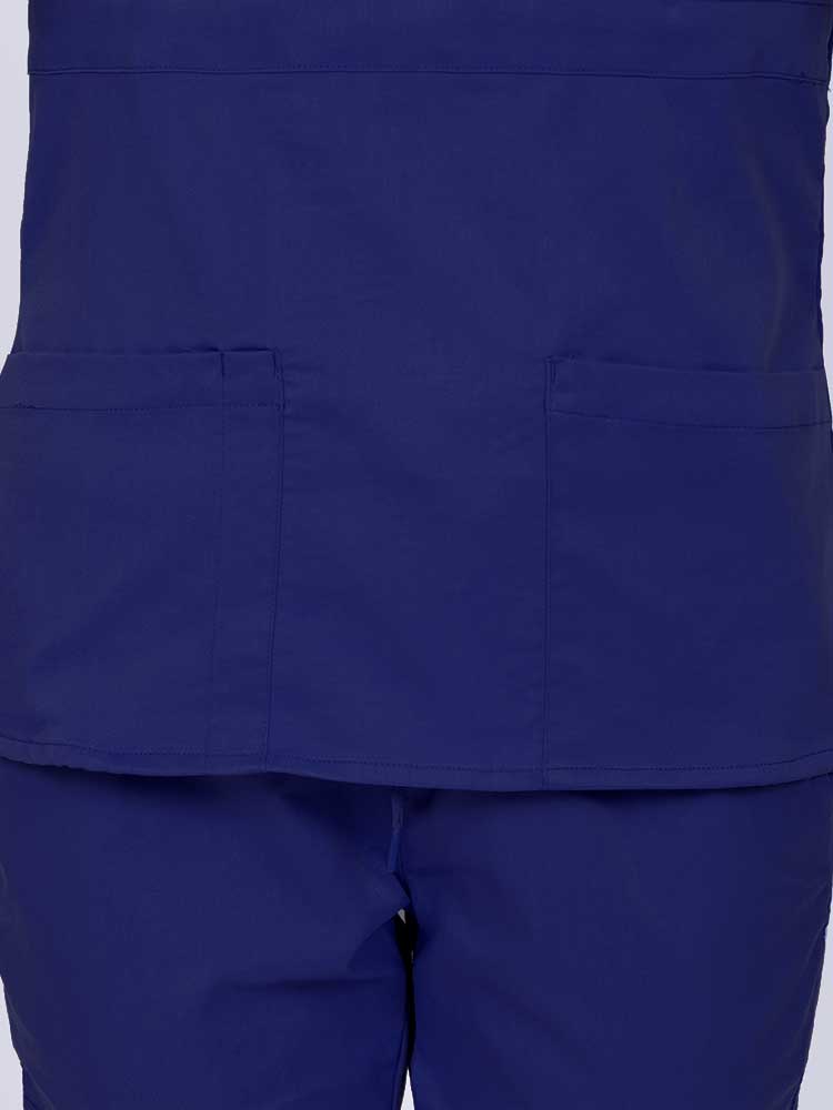 Woman wearing an Epic by MedWorks Women's Mock Wrap Scrub Top in navy featuring two front patch pockets.