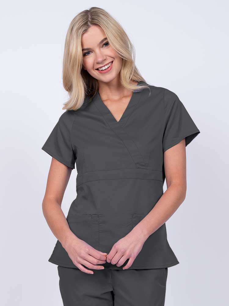 Young woman wearing an Epic by MedWorks Women's Mock Wrap Scrub Top in pewter with a unique fabric content of 77% Polyester, 21% Viscose, 2% Spandex.