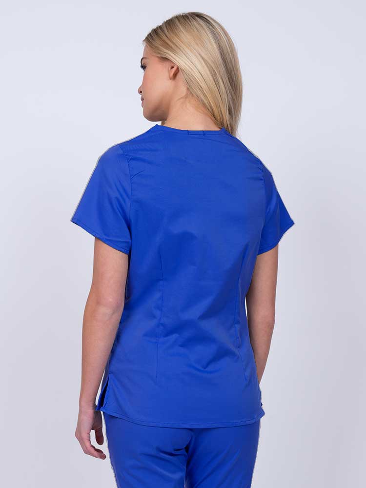 Nurse wearing an Epic by MedWorks Women's Mock Wrap Scrub Top in royal with side slits for additional range of motion.