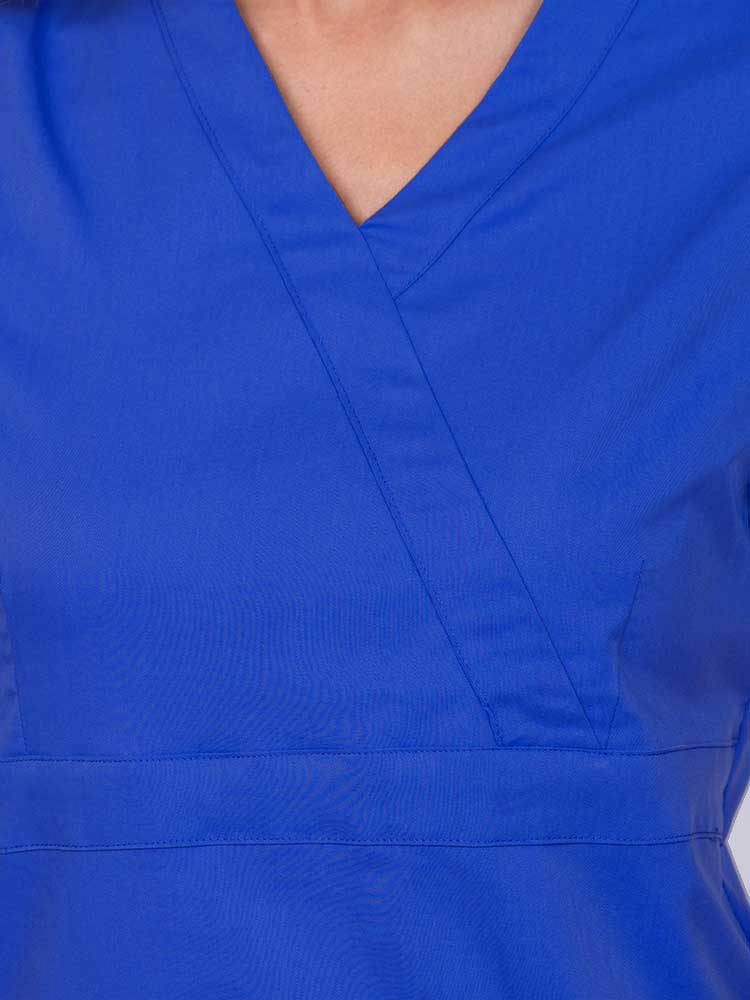 Young woman wearing an Epic by MedWorks Women's Mock Wrap Scrub Top in royal featuring a mock wrap neckline and stylish front seaming.