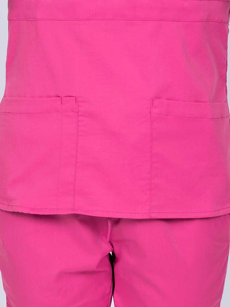 Woman wearing an Epic by MedWorks Women's Mock Wrap Scrub Top in shocking pink featuring two front patch pockets.