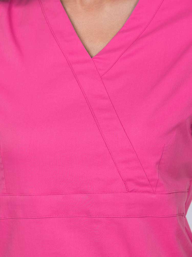 Young woman wearing an Epic by MedWorks Women's Mock Wrap Scrub Top in shocking pink featuring a mock wrap neckline and stylish front seaming.