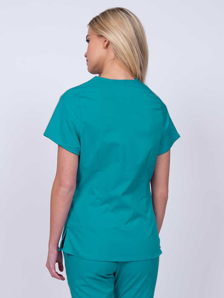 Nurse wearing an Epic by MedWorks Women's Mock Wrap Scrub Top in teal with side slits for additional range of motion.