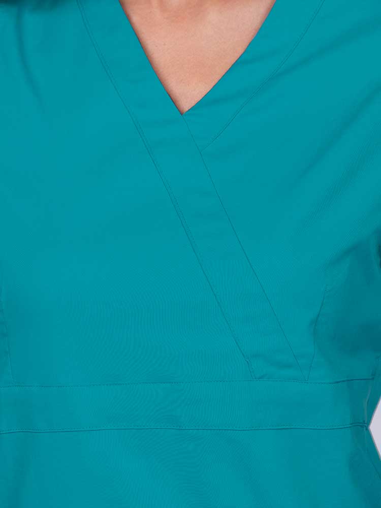 Young woman wearing an Epic by MedWorks Women's Mock Wrap Scrub Top in teal featuring a mock wrap neckline and stylish front seaming.