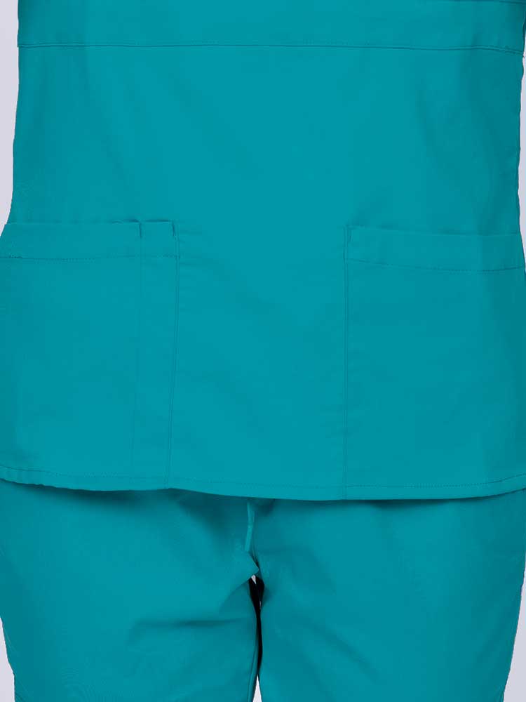 Woman wearing an Epic by MedWorks Women's Mock Wrap Scrub Top in teal featuring two front patch pockets.