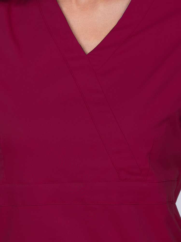 Young woman wearing an Epic by MedWorks Women's Mock Wrap Scrub Top in wine featuring a mock wrap neckline and stylish front seaming.