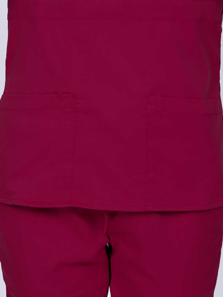 Woman wearing an Epic by MedWorks Women's Mock Wrap Scrub Top in wine featuring two front patch pockets.