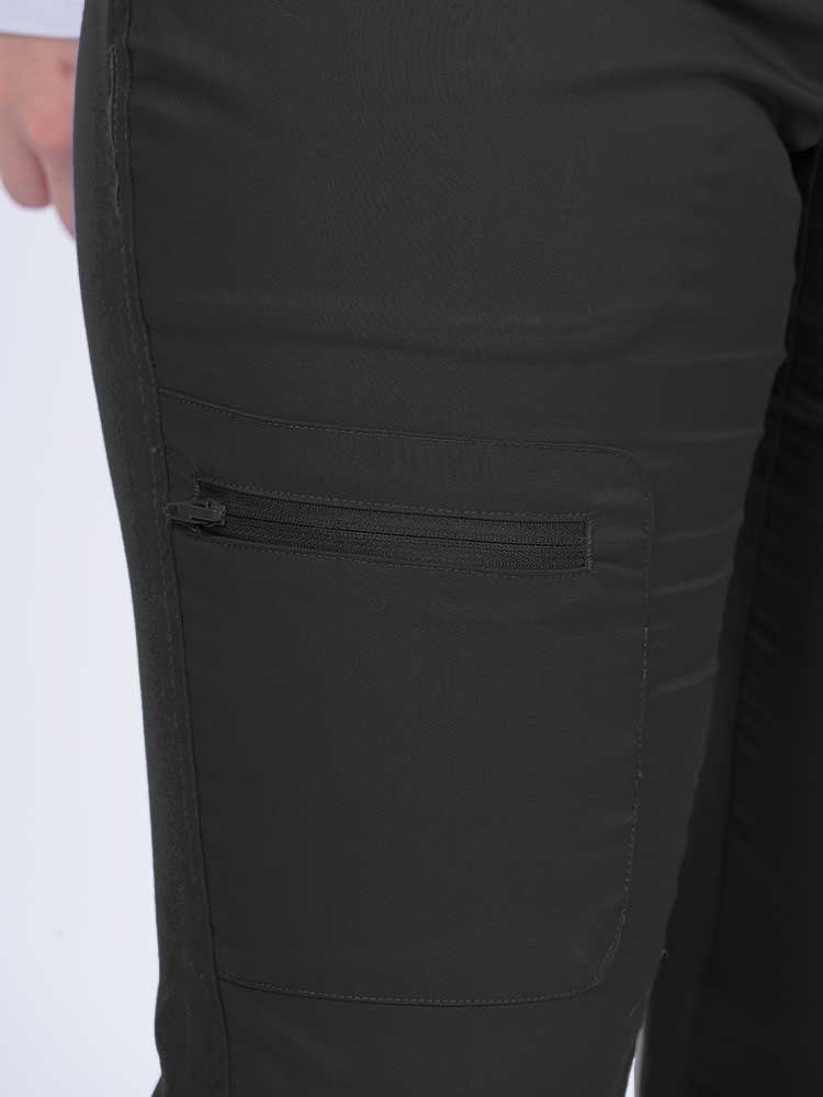 Young female nurse wearing an Epic by MedWorks Women's Blessed Skinny Yoga Scrub Pant in black with 1 zip closure cargo pant on the wearer's right.