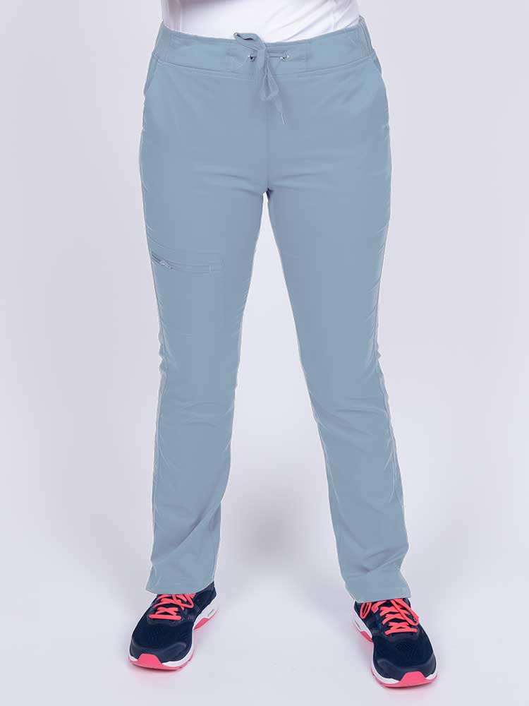 Young healthcare worker wearing an Epic by MedWorks Women's Blessed Skinny Yoga Scrub Pant in blue fog featuring side slits for additional range of motion.