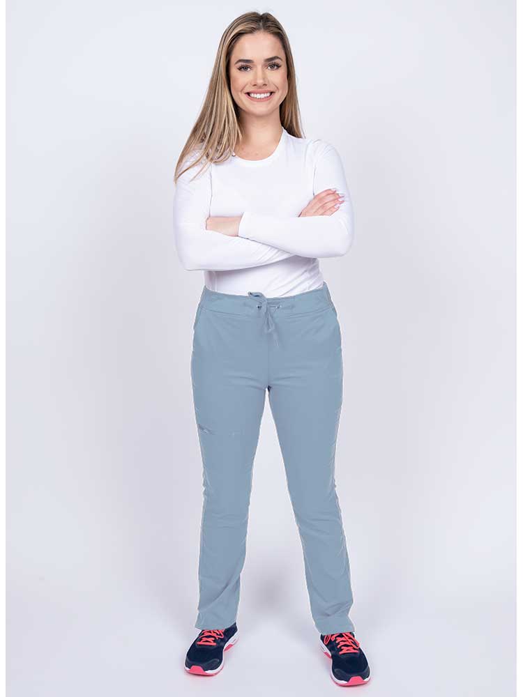 Young woman wearing an Epic by MedWorks Women's Blessed Skinny Yoga Scrub Pant in blue fog with an adjustable waistband.