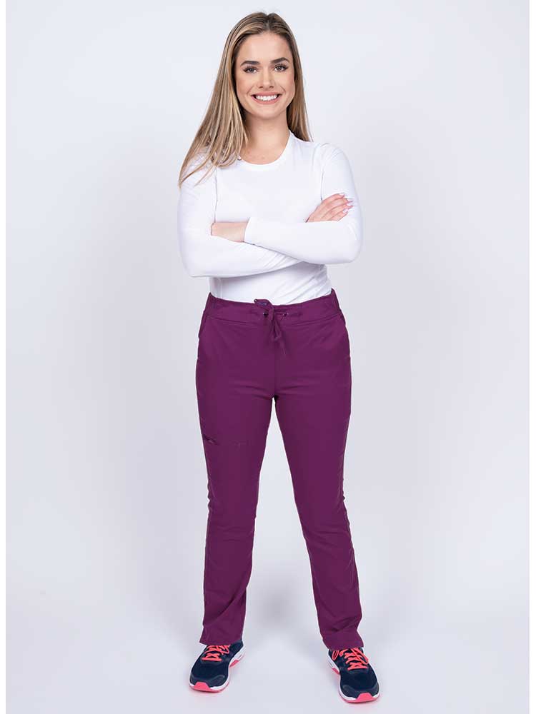 Young woman wearing an Epic by MedWorks Women's Blessed Skinny Yoga Scrub Pant in eggplant with an adjustable waistband.