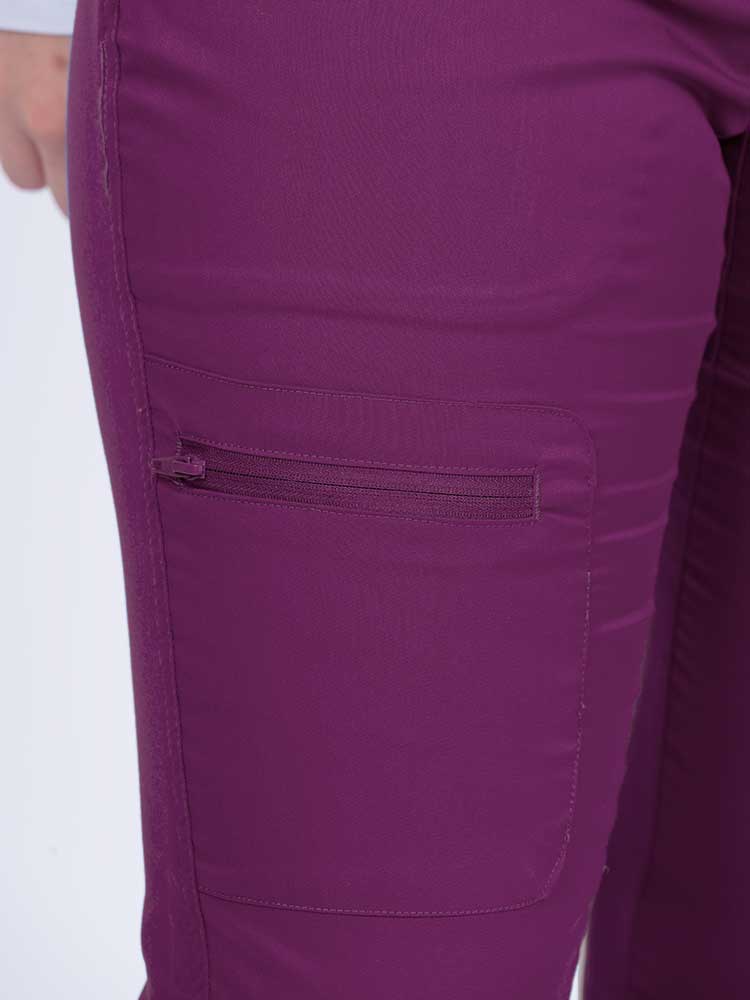 Young female nurse wearing an Epic by MedWorks Women's Blessed Skinny Yoga Scrub Pant in eggplant with 1 zip closure cargo pant on the wearer's right.