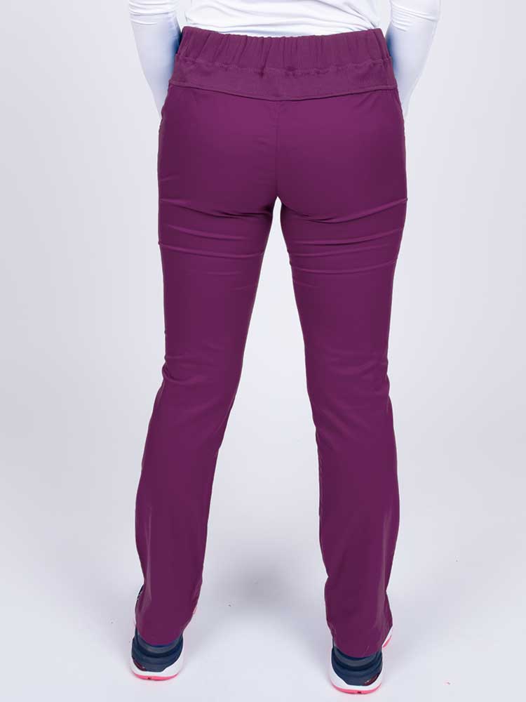 Nurse wearing an Epic by MedWorks Women's Blessed Skinny Yoga Scrub Pant in eggplant with a knit waistband.