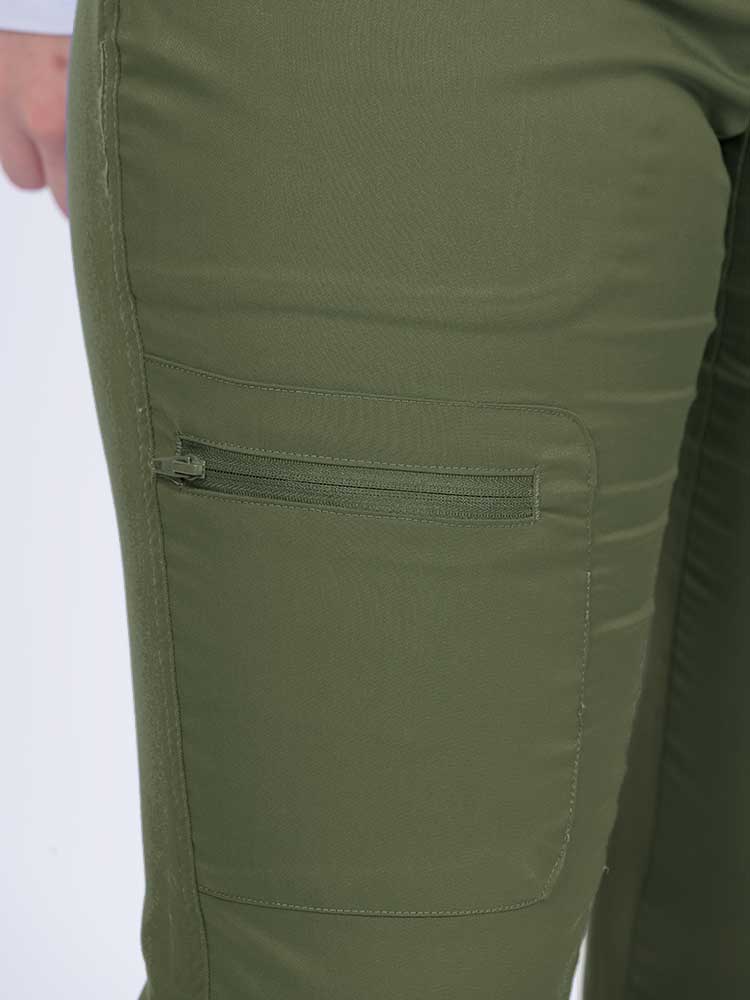 Young female nurse wearing an Epic by MedWorks Women's Blessed Skinny Yoga Scrub Pant in olive with 1 zip closure cargo pant on the wearer's right.