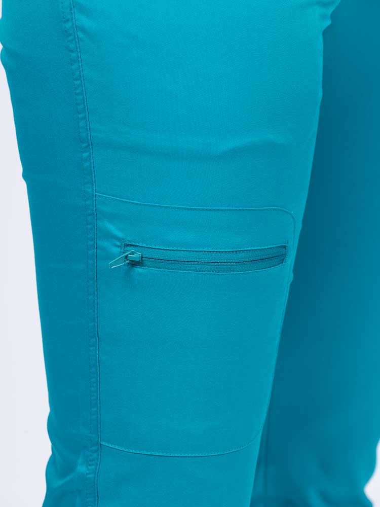 Young female nurse wearing an Epic by MedWorks Women's Blessed Skinny Yoga Scrub Pant in teal with 1 zip closure cargo pant on the wearer's right.