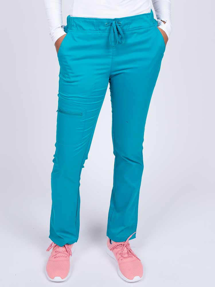 Young healthcare worker wearing an Epic by MedWorks Women's Blessed Skinny Yoga Scrub Pant in teal featuring side slits for additional range of motion.
