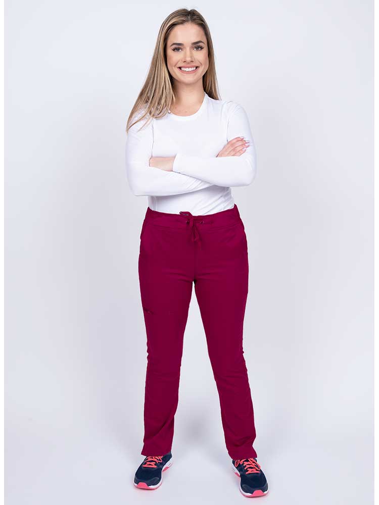 Young woman wearing an Epic by MedWorks Women's Blessed Skinny Yoga Scrub Pant in wine with an adjustable waistband.