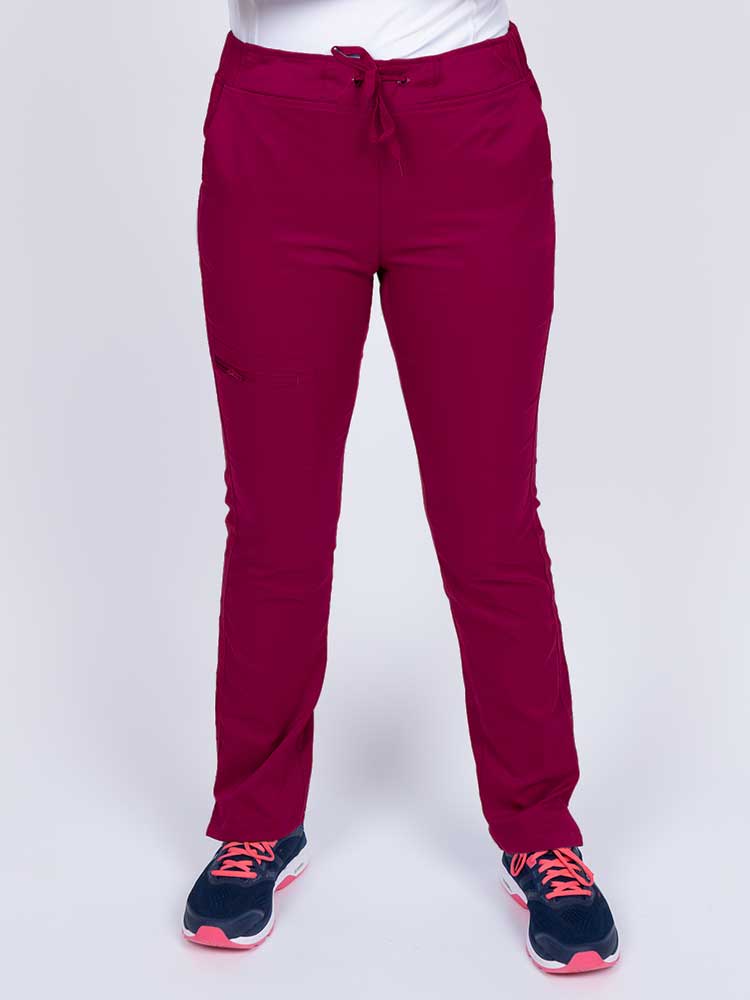 Young healthcare worker wearing an Epic by MedWorks Women's Blessed Skinny Yoga Scrub Pant in wine featuring side slits for additional range of motion.
