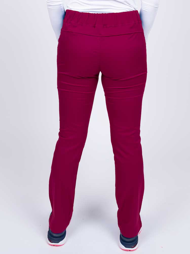 Nurse wearing an Epic by MedWorks Women's Blessed Skinny Yoga Scrub Pant in wine with a knit waistband.
